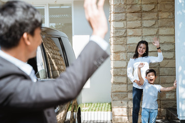 portrait of asian father waving goodbye to his family before going to work