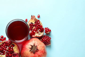 Glass of pomegranate juice and fresh fruits on color background, top view with space for text