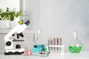 Laboratory glassware and microscope on table indoors. Chemistry concept