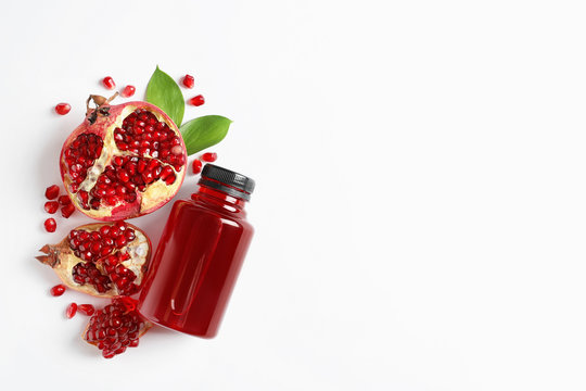 Bottle of pomegranate juice and fresh fruits on white background, top view