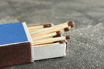 Open box with matches on grey background, space for text
