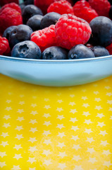 raspberries and blueberries fruit in a bowl in jolly summer style 
