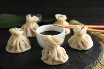 Slate plate with tasty baozi dumplings, chopsticks and soy sauce on table