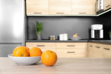 Fresh oranges on wooden table in kitchen. Space for text
