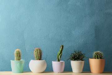 Different potted cacti on table near color background, space for text. Interior decor
