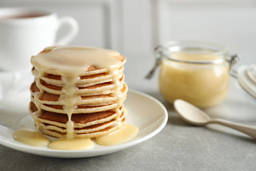 Plate with pancakes and condensed milk served on table, space for text. Dairy product