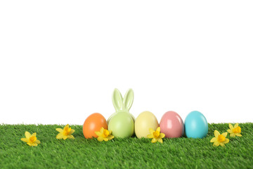 Dyed Easter eggs and bunny ears on green grass against white background