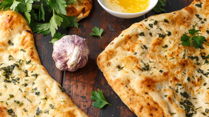 Indian naan bread with garlic butter on wooden table