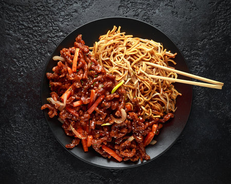egg noodles with bean sprouts and Crispy shredded beef on black plate