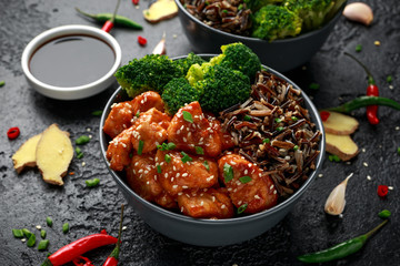Teriyaki chicken, steamed broccoli and wild rice served in two Asian clay bowls