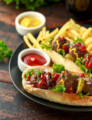 Meat balls hotdogs with french potato fries, chips, crinkle cut gherkins, ketchup and mustard. fast food