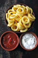 Corn rings in a bowl with red and white sauce. Flat Lay.