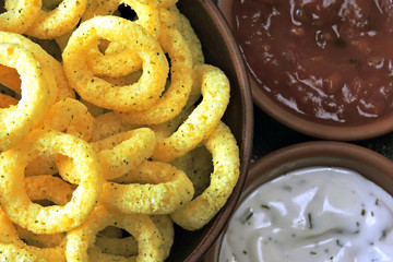Corn rings in a bowl with red and white sauce. Flat Lay.