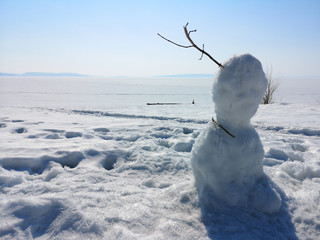 Clumsy snowman on the background of Russian winter landscape