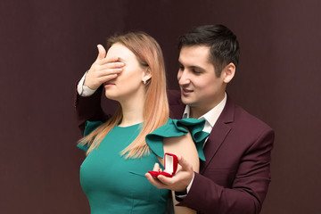 The man prepared a surprise gift for the bride. The man covered his girlfriend hand with his hand.