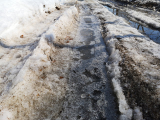 Winter melting snow on the road closeup, early spring