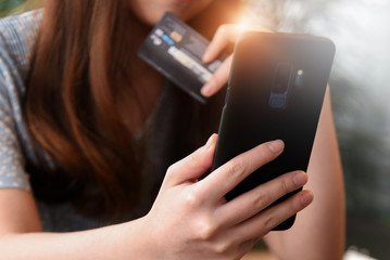 Woman hands holding smart phone and using credit card for online shopping.Online shopping concept.Close up