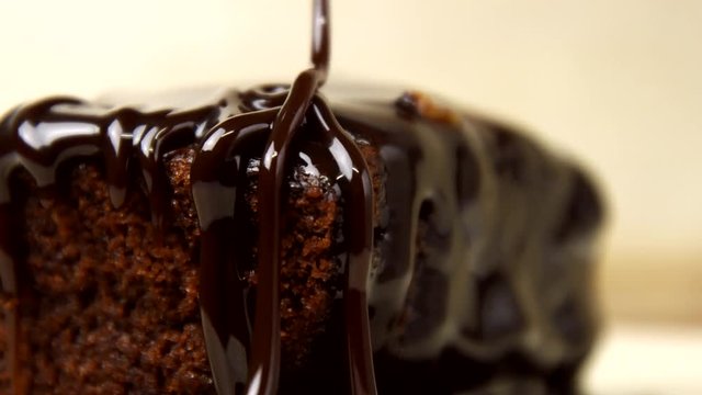 Chocolate icing on cake. Topping chocolate dessert. Chocolate glaze pouring on homemade dessert. Close up of biscuit cake decoration in 4K resolution