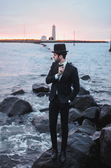 Fototapeta na wymiar Man in the suit by the sea next to the lighthouse