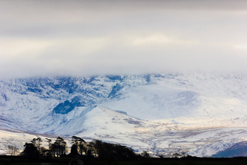 Fototapeta na wymiar View of the spectacular snow-covered Snowdonia Mountain Range from Pentraeth on the Isle of Anglesey