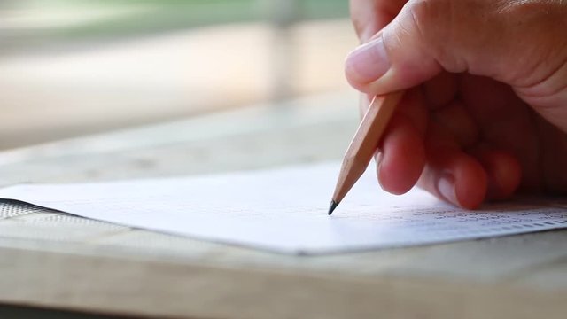Education school test concept : Hands student holding pencil for testing exams writing answer sheet or exercise for taking fill in admission exam multiple carbon paper computer at university classroom