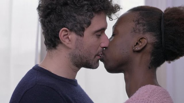 Caucasian man and african woman kissing,looking into each others eyes