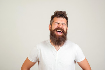 Stylish happy bearded man with closed eyes shouting on white background. Male excited face expression. Handsome bearded guy screaming.
