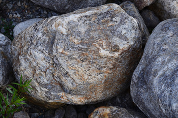 Round patterned stones at the mountain river or sea or ocean. One big stone in the middle close up. Texture or wallpaper