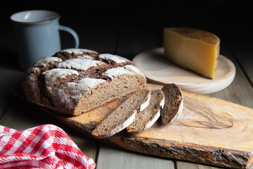 sliced rye bread on a rustic table with a plaid cloth and a cheese