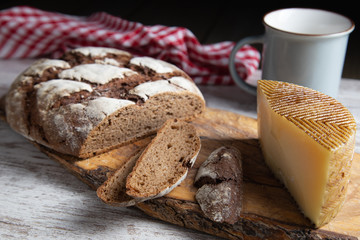 sliced rye bread on a rustic table with a plaid cloth a cheese and a mug
