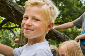 Junge steht mit Freunden vorm Zaun eines Tiergeheges