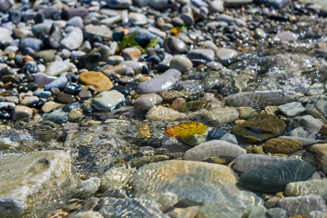 pebble stones on the sea beach, the rolling waves of the sea with foam