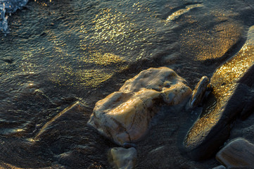pebble stones on the sea beach, the rolling waves of the sea with foam