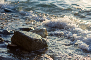 rocky sea shore with pebble beach, waves with foam