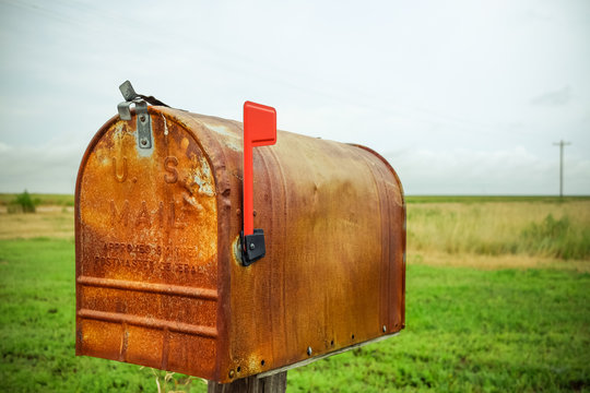 An Old Rusty Mailbox In A Field.