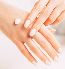 Young female hands applying moisturizing cream.