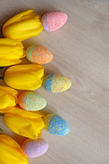 decorative easter eggs and yellow tulips on wooden background