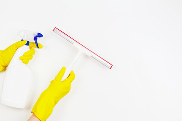 Woman hands with yellow rubber gloves holding window glass cleaning tool and spray bottle with detergent over white background