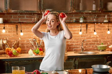 Eat healthy, stay healthy. Happy young woman cooking vegetables in modern kitchen. Cozy interior