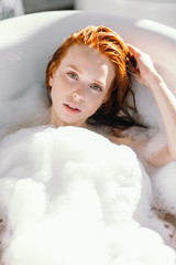 Sensual sexy woman with long ginger hair, natural looking pretty face expresses satisfaction with...