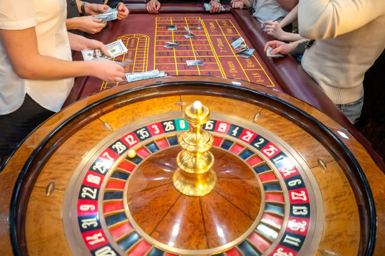 A table with a roulette in a casino. The croupier gives out a prize. Gambling for money. People make bets on roulette. Underground Casino.