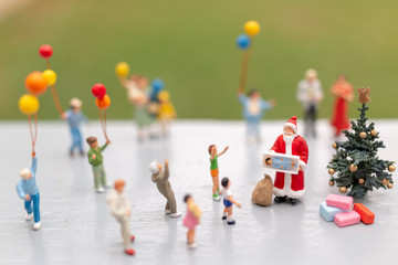 Miniature people : Santa Claus holding gift for happy family , Christmas and Happy New Year concept.