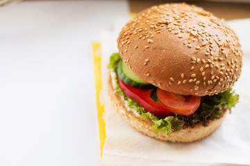 Hamburger with beef, cheese and vegetables on rustic table. Closeup with copy space