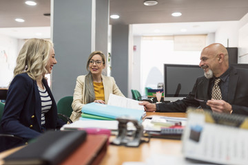 office workes talking and looking files: women and mature boss at desk