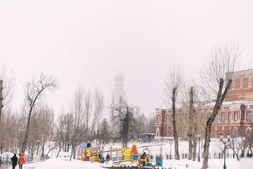 Melting snow and fog in the city. Playground, beautiful building and church in the urban landscape.