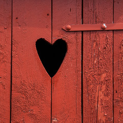 Heart carved in red wooden door. Close up. Copy space.