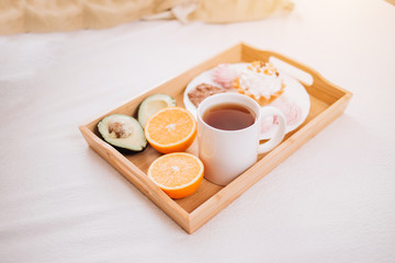 Young woman eating healthy breakfast in bed