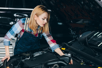Fototapeta na wymiar engines trend monitoring. cute blonde learning to fix the car. close up photo. unusual job for women