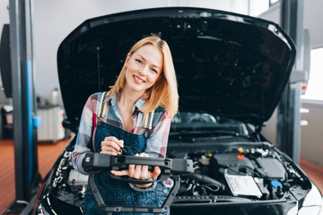cheerful positive female mechanic with digital tablet looking at the camera, favourite hobby. copy...