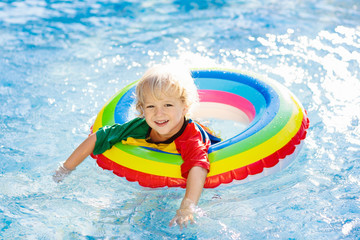 Child in swimming pool on toy ring. Kids swim.